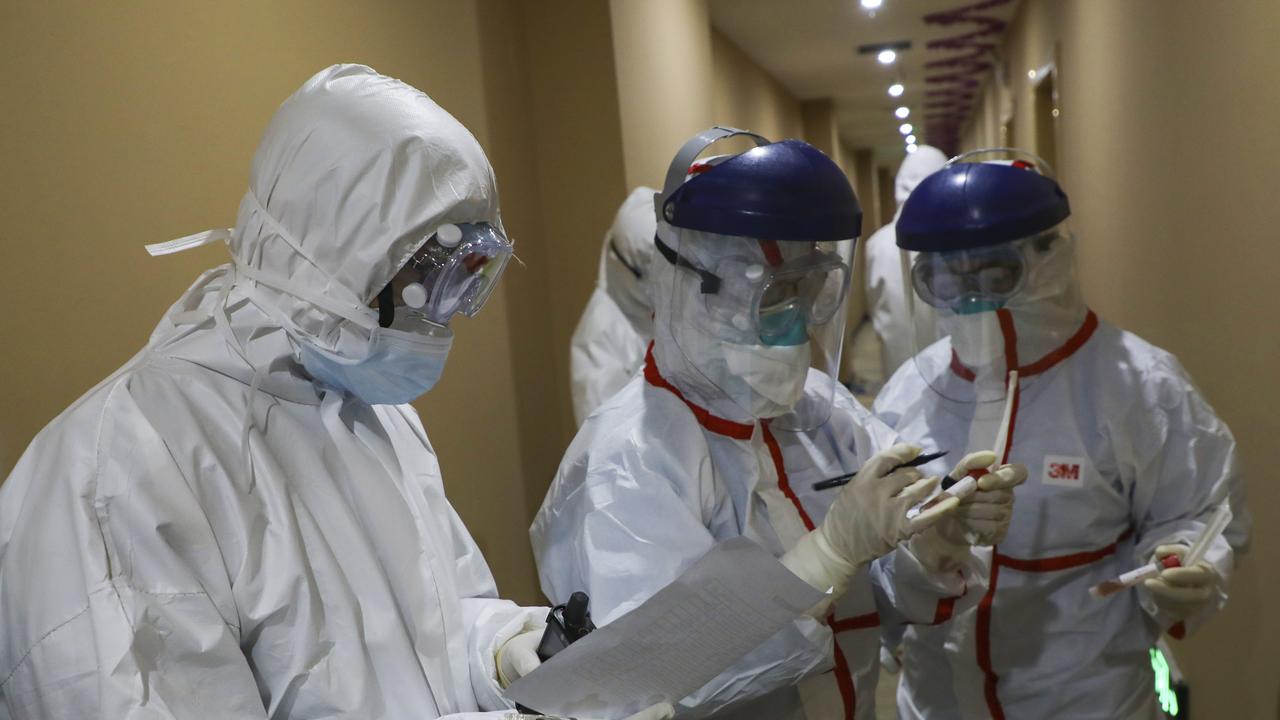 A medical worker in a protective suit collects a sample for testing from a suspected virus patient at a hotel in Wuhan. Picture: Chinatopix via AP