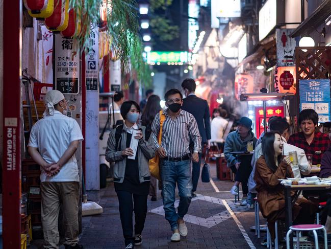 People wearing face masks as a preventive measure against the Covid-19 coronavirus visit the restaurant area of Omoide Yokocho alleyway in Shinjuku district of Tokyo on November 19, 2020. (Photo by Philip FONG / AFP)