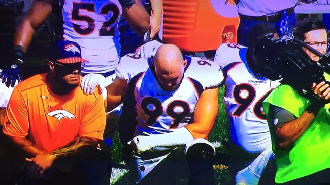Denver Broncos' Australian defensive end Adam Gotsis (99) takes a knee during the American National Anthem.