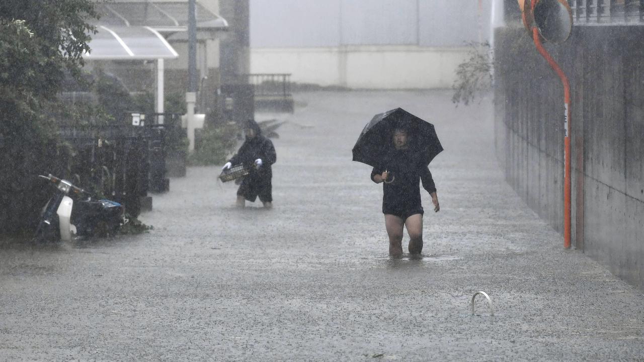 People walk through a flooded street affected by Typhoon Hagibis, in Shizuoka, central Japan Saturday.