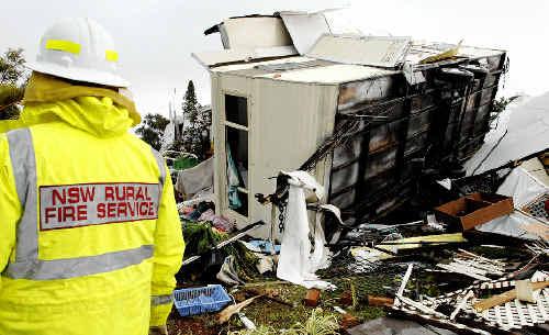 WRECKED: A NSW Rural Fire Service firefighter inspects a wreckedcaravan at the Lake Ainsworth Caravan Park after yesterday’s tornado. Picture: Jay Cronan