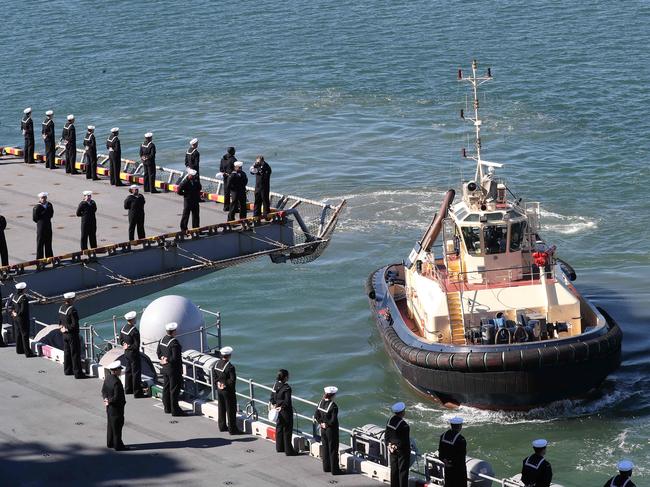 Sailors “man the rails” in a US Navy tradition upon entering a foreign port, as one of three tugboats guides the USS America into the Port of Brisbane. Picture: Liam Kidston