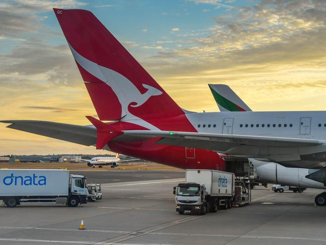 ESCAPE: PH5KGJ Tail fin of a Qantas Airbus A380 "super jumbo" jet at London Heathrow airport with a sunset sky. A truck is loading air freight into its hold. Picture: Alamy