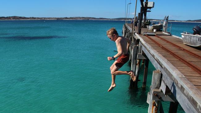 KANGAROO ISLAND, AUSTRALIA - FEBRUARY 25: Young boys jump off Vivonne Bay Jetty into the water on February 25, 2020 in Kangaroo Island, Australia. Over a third of Kangaroo Island, including much of the Flinders Chase National Park, was burnt during the recent bushfires that started on 4 January. Two people lost their lives, while tens of thousands of native animals and farming livestock were also killed. The Wildlife, Ecosystems and Habitat Bushfire Recovery Taskforce estimates as many as 90 percent of Kangaroo Island's famous koala population perished in the recent bushfires, with only 5,000 to 10,000 koalas remaining in the area from an original population of about 60,000. Kangaroo Island's economy is reliant on agriculture and tourism Ã¢â¬â worth an estimated 180 million dollars Ã¢â¬â and focus is now turning to reviving the industries post the bushfires. The South Australian Tourism Commission launched the #BookThemOut campaign to encourage tourists to visit the bushfire affected areas in the Adelaide Hills and Kangaroo Island, with the recent Kangaroo Cup Racing Carnival reaching record attendance this past weekend. However, with the Island known to be a popular tourism destination for Chinese tourists the local industry is now also being heavily affected by coronavirus.The Federal Government has announced a royal commission into this summer's devastating bushfires across Australia, with a specific focus on preparedness for future bushfire seasons. Former Australian Defence Force (ADF) chief Mark Binskin, former Federal Court judge Annabelle Bennett and leading environmental lawyer Andrew Macintosh are due to deliver their findings by the end of August. (Photo by Lisa Maree Williams/Getty Images)