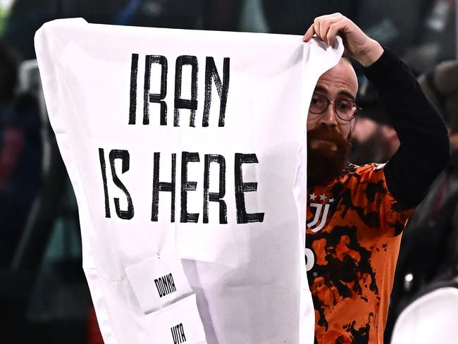 A fan holds a banner on the tribune which reads as âIran is Here - woman, life, freedom" during the UEFA Women's Champions League Group C football match between Juventus and Arsenal at the Juventus stadium in Turin on November 24, 2022. (Photo by MARCO BERTORELLO / AFP)