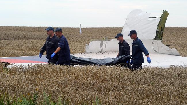 Ukrainian rescue workers walk past a piece of wreckage as they carry the body of a victim on a stretcher at the site of the crash of a Malaysia Airlines plane carrying 298 people from Amsterdam to Kuala Lumpur in Grabove, in rebel-held east Ukraine, on July 19, 2014