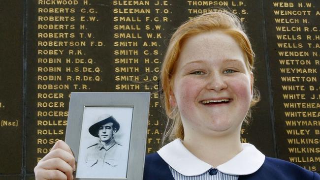 Emily Webb holds a photo of Henry Webb , in front of the Cenotaph at Alan Border Oval that bears his name. Picture: John Appleyard