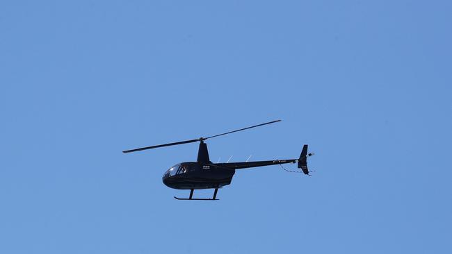 A helicopter used to spot sharks flies over Burleigh Heads after a recent run of shark sightings on the Gold Coast. Photograph: Jason O’Brien.