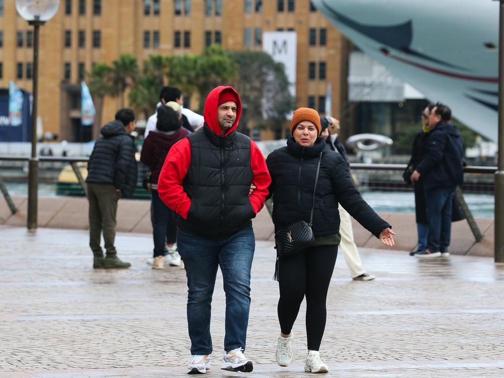 People are seen rugged up in winter clothing walking along Circular Quay during a low pressure system that has caused the coldest day of the year. Picture: Newswire / Gaye Gerard