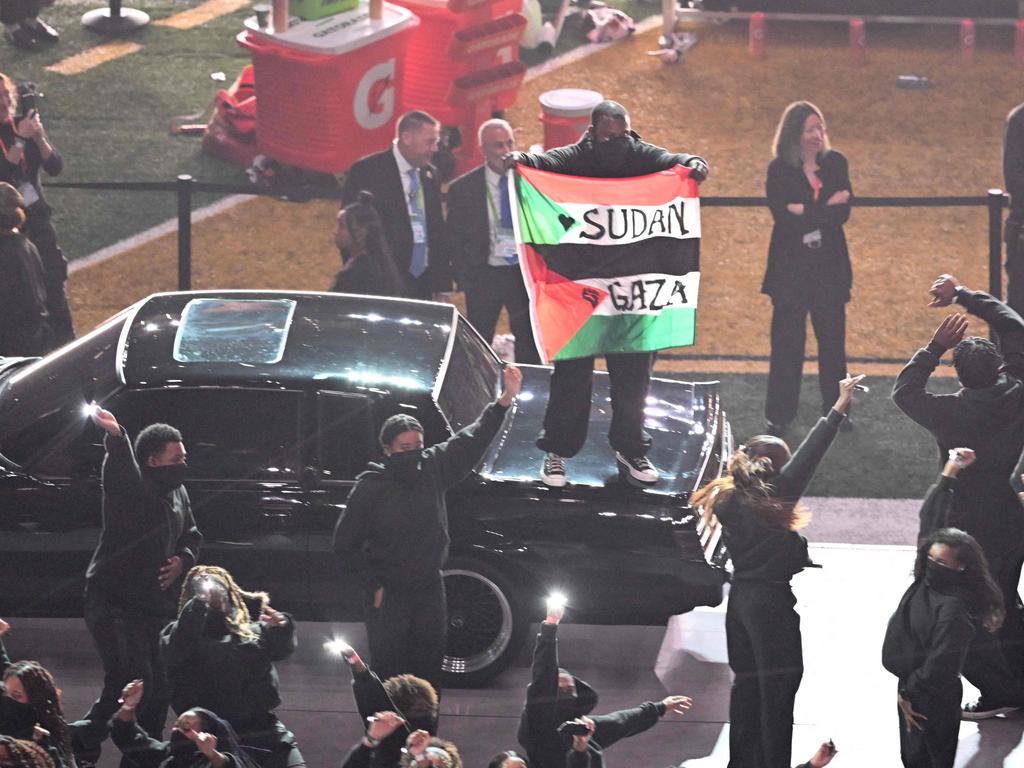 A protester holds a Palestinian flag with the words 'Gaza' and 'Sudan' as US rapper Kendrick Lamar performs during Super Bowl LIX. Picture: AFP