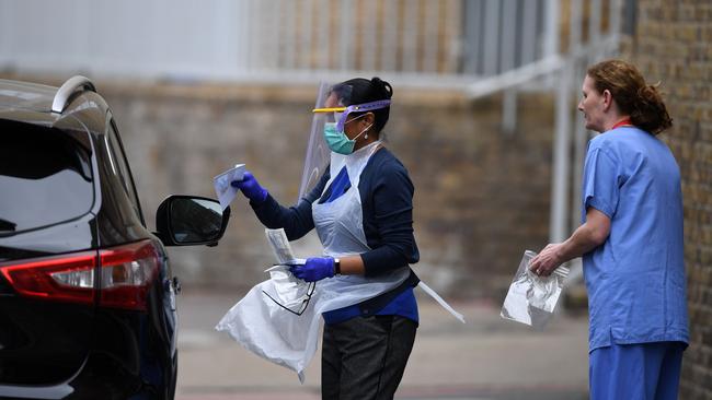 A medical worker hands an essential worker a testing kit for COVID-19 at a drive-in testing facility in east London on Saturday. Picture: AFP