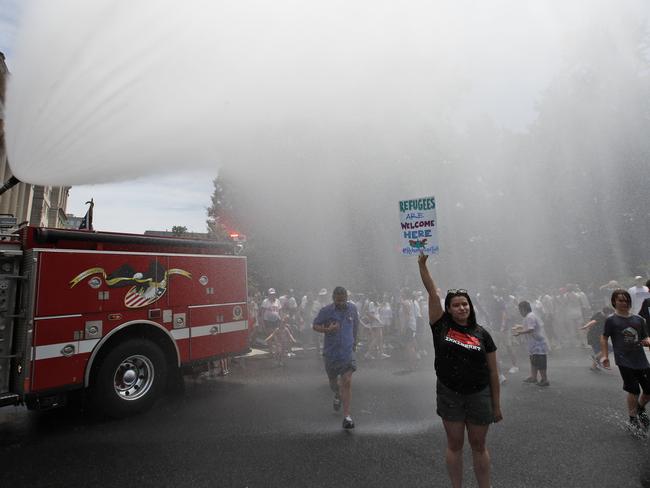 Maria Zamora, from Newark, New Jersey, stands in the water spray from a firetruck during a protest of the Trump administration's approach to illegal border crossings. Picture: AP