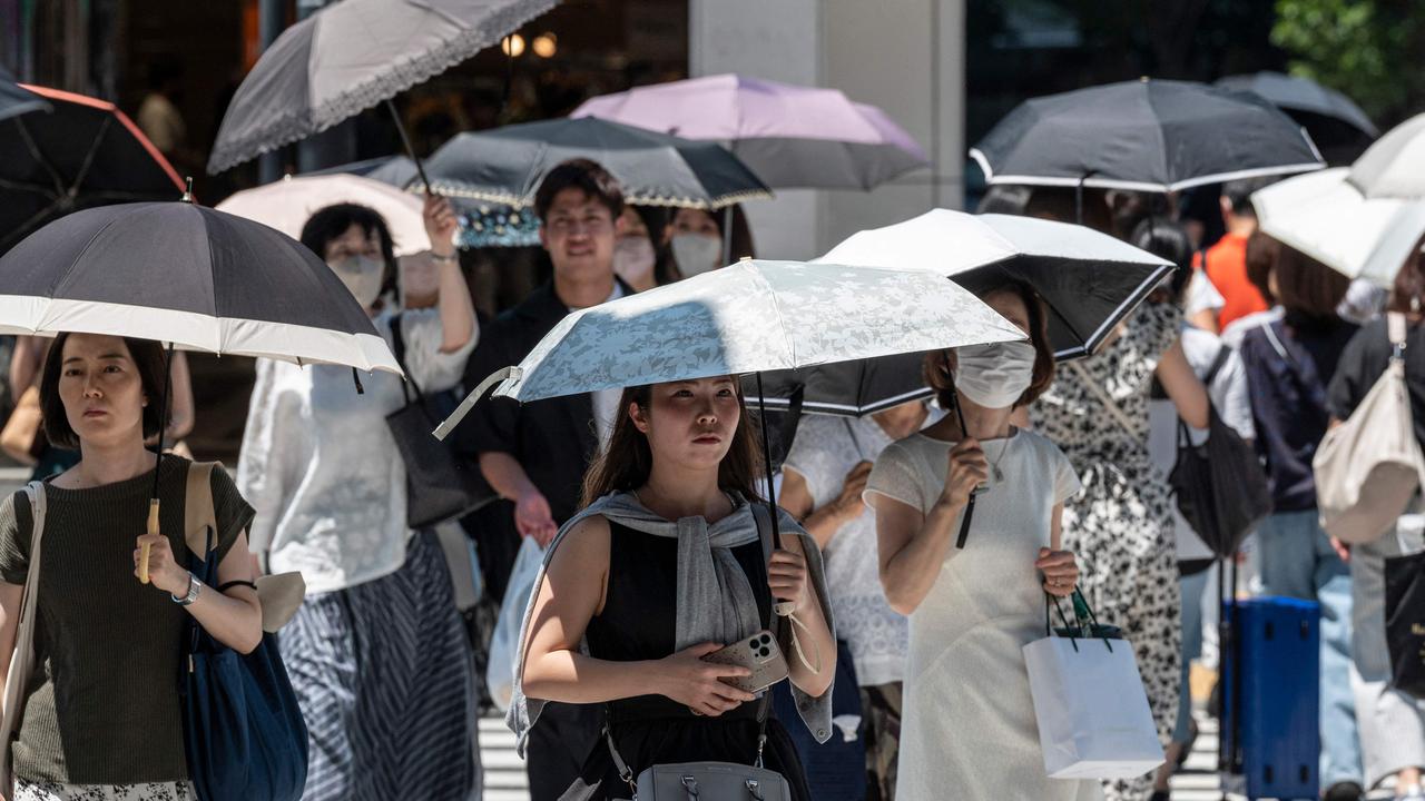 Pedestrians use umbrellas to shelter from the midday sun as they cross the street in downtown Tokyo as scorching heat blisters the Northern Hemisphere. Picture: AFP