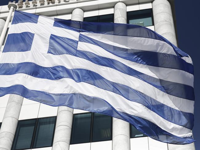 FILE - In this Feb. 3, 2015, file photo, a Greek flag flies outside the Athens Stock Exchange. In 2012, financial markets were rattled by the possibility Greece would elect a left-wing government, default on their debts and drop the euro currency. In 2015, the left-wing party, Syriza, holds power in Athens. Greece actually did miss a loan payment to the International Monetary Fund late Tuesday, June 30, 2015. And the nation's future in the eurozone hinges precariously on a referendum Sunday, July 5, 2015. (AP Photo/Petros Giannakouris, File)