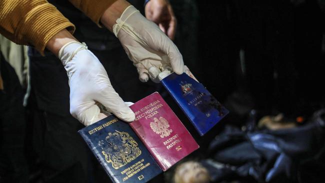 A man displays British, Polish, and Australian passports next to the bodies of World Central Kitchen workers at Al-Aqsa Hospital in Deir al-Balah, Gaza Strip. Picture: AFP.