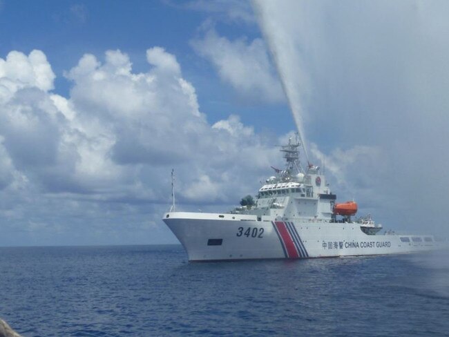 A, Chinese Coast Guard members approach Filipino fishermen as they confront each other off Scarborough Shoal in the South China Sea. Picture: AP