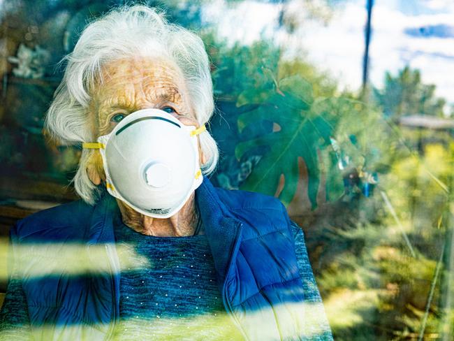 Distraught Elderly Senior Caucasian Woman Looking Out the Window Feeling Loneliness Wearing an n95 Protective Face Mask To Prevent the Spread of Covid. aged care generic