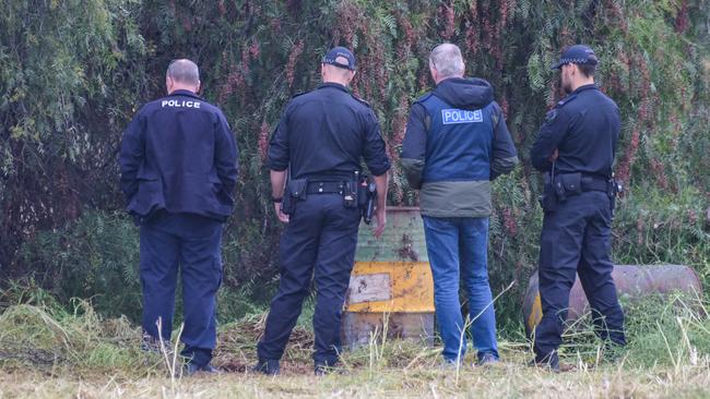 Police examine barrels left the rear of the vacant block. Picture: Brenton Edwards