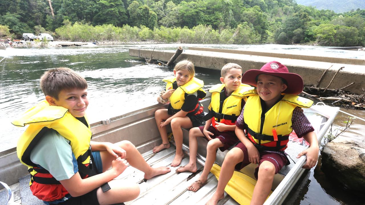 Gordonvale State High School student Hayden, Gordonvale Primary School student Kyrah with St Michael’s School pupils Rubus and Archer McKowens board a boat to cross the Mulgrave River after the Fisheries Bridge was washed away by flood water. Picture: Peter Carruthers