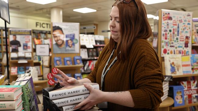 A member of staff sticks "half price" stickers on "Spare",at the WH Smith bookstore, at Victoria Station in London. Picture: AFP.