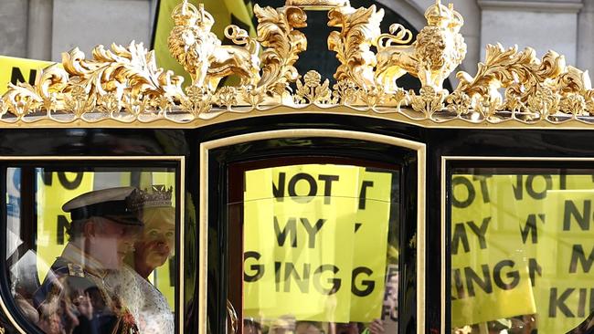 TOPSHOT - Britain's King Charles III and Britain's Queen Camilla travel in the Diamond Jubilee State Coach past protesters holding "Not My King" placards, from the anti-monarchy group Republic as they demonstrate ahead of the State Opening of Parliament, opposite the Houses of Parliament in London on November 7, 2023. (Photo by HENRY NICHOLLS / AFP)