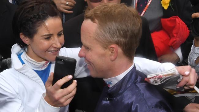 Michelle Payne hands the phone to Kerrin McEvoy to speak to his wife Cathy after his Cup-winning ride. Photo by Vince Caligiuri/Getty Images