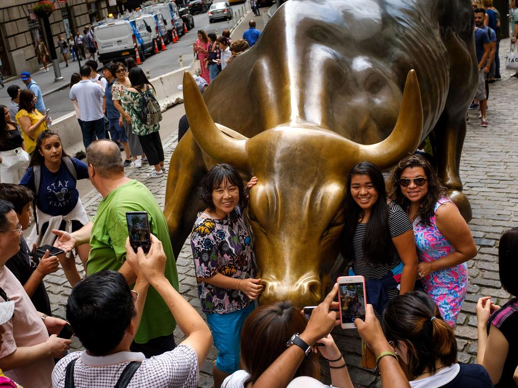 Tourists pose with the famous Wall Street bull statue in New York’s Financial District. Picture: Drew Angerer/Getty Images/AFP