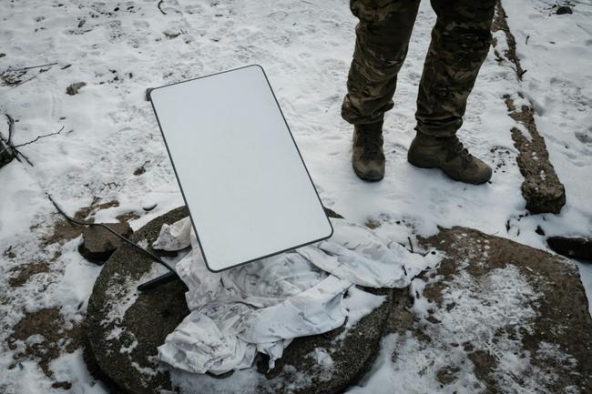 A Ukrainian serviceman stands next to the antenna of a Starlink satellite-based broadband system in Bakhmut in February 2023