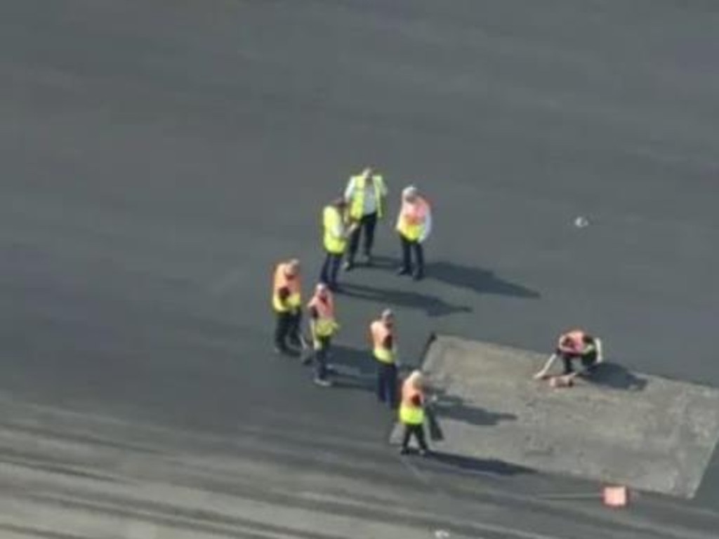 Workers at Luton Airport examine the runway after it melted due to the scorching weather.
