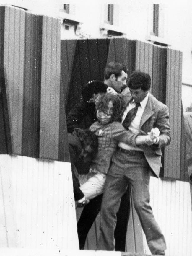 A male intruder, 19, is apprehended after breaking onto official dias and waving a Eureka flag near the Queen during the opening of the Adelaide Festival Centre southern plaza and Hajek sculptures.