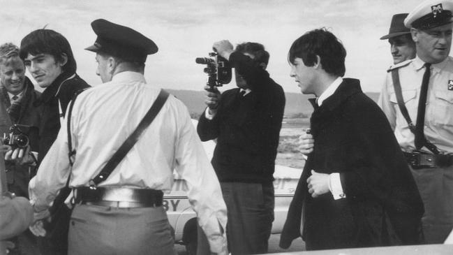 Former Advertiser journalist Jonathon Stone, far left behind George Harrison, covering The Beatles' arrival in Adelaide on June 12, 1964, with Paul McCartney, right. Picture: Advertiser staff photographer.