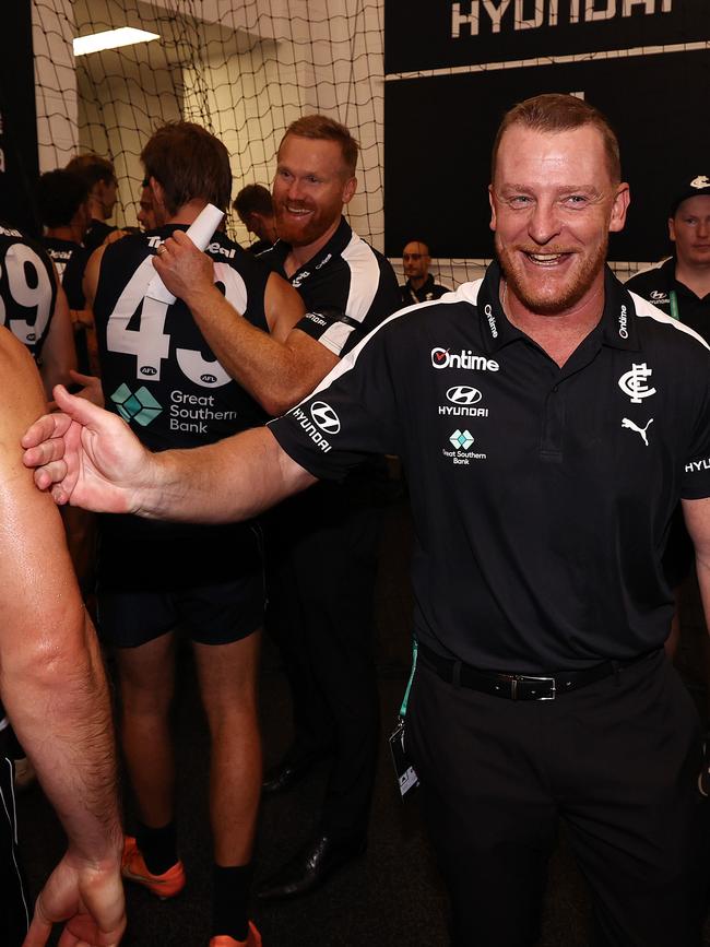 A happy Michael Voss with players in the rooms post-match.