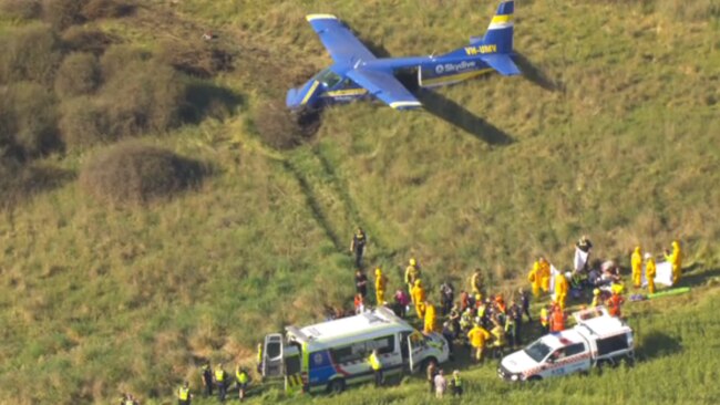 空中镜头显示紧急救援人员在距离受损飞机数米处工作。