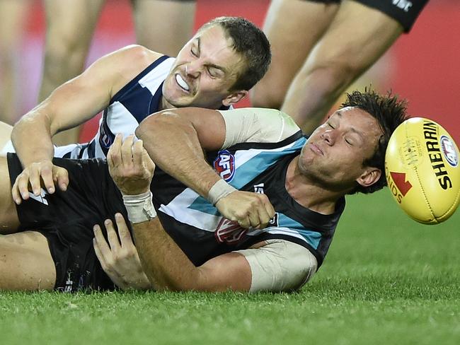 GOLD COAST, AUSTRALIA - AUGUST 14: Steven Motlop of the Power handballs whilst being tackled by Tom Atkins of the Cats during the round 12 AFL match between the Geelong Cats and the Port Adelaide Power at Metricon Stadium on August 14, 2020 in Gold Coast, Australia. (Photo by Matt Roberts/Getty Images)