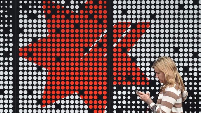 (FILES) In this file photo taken on November 1, 2017 a woman walks past a National Australia Bank (NAB) branch in Sydney. National Australia Bank announced plans to sell down its wealth management arm on May 3, 2018 as it continues to offload assets to simplify its business.  / AFP PHOTO / PETER PARKS