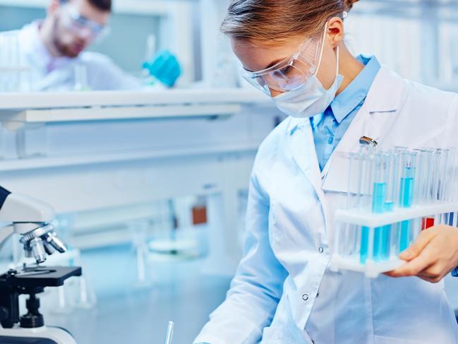 HEALTH:  Young woman with flasks making notes in laboratory. Biotechnology research  laboratory generic