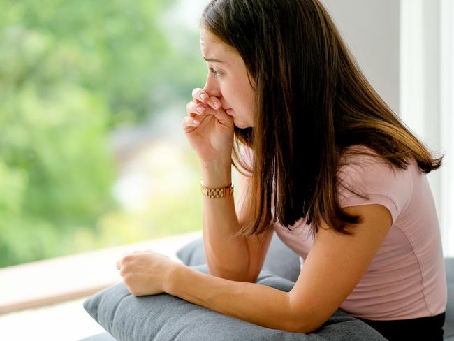 Portrait of beautiful woman express sad and dismal emotion sit near glass windows in room of her house. Concept of mental health problem can occur to various people especially during covid pandemic.