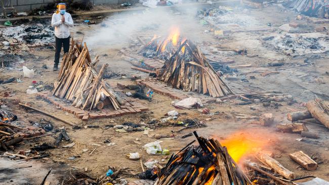 A man prays next to a burning pyre of a realive who died of Covid-19 in New Delhi. Picture; AFP.