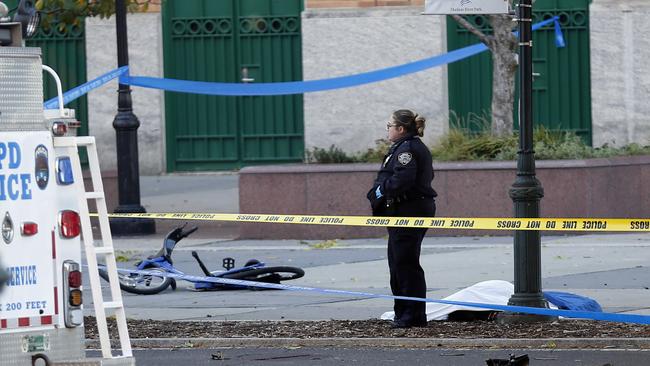 A New York Police Department officer stands next to a body covered under a white sheet near a mangled bike in New York. Picture: AP