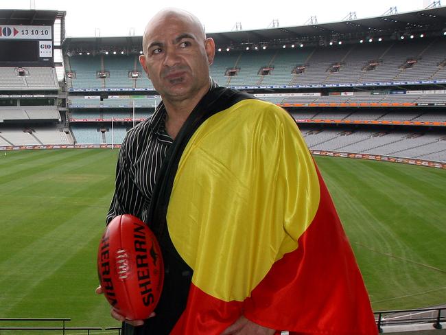 Former AFL footballers Michael Long (Essendon) and Phil Egan (Richmond) at the MCG promoting the AFL indigenous round.Long has the Torres Strait Islands flag and Egan has the Aboriginal flag.