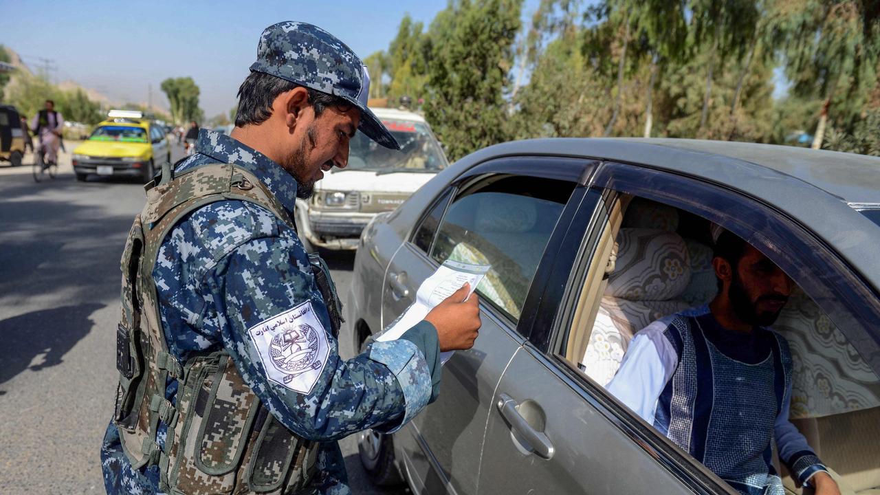 A Taliban fighter checks the identity and vehicle documents of cars passing through Kandahar. Picture: Javed Tanveer/AFP