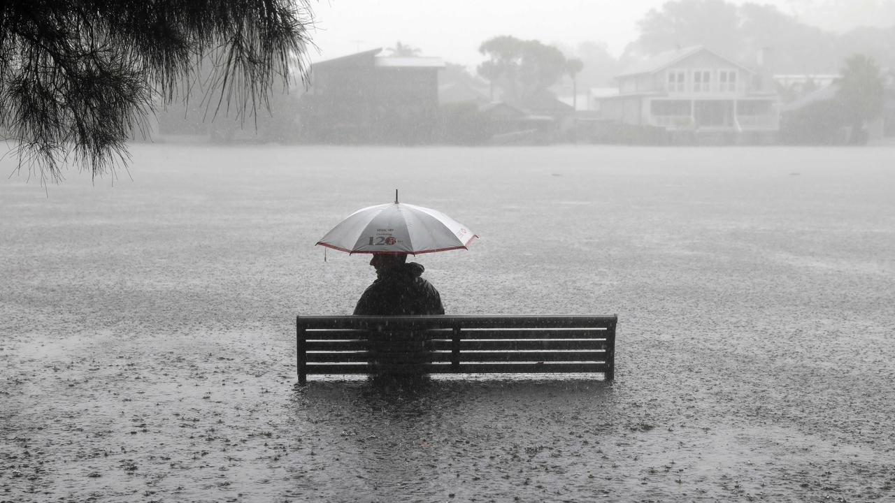 A customer sits in the flooded carpark at the Narrabeen Woolworths store. Picture: Damian Shaw
