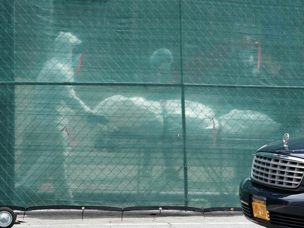 A body is removed from a refrigeration truck serving as a temporary morgue at the Brooklyn Hospital Centre. Bodies piling up on streets in full view of pedestrians is not an uncommon sight. Picture: AFP