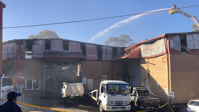 Fire and Rescue NSW was still pouring water onto the smouldering ruins of the Hart’s Automotive Services on Tuesday afternoon. Picture: Jim O'Rourke