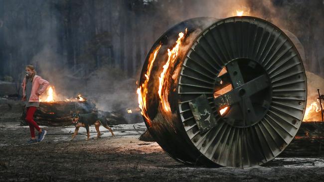 A burning NBN cable spool on scorched land at Mallacoota, Victoria. Picture: David Caird