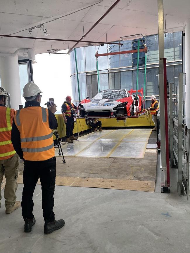 Workers guide the car inside.