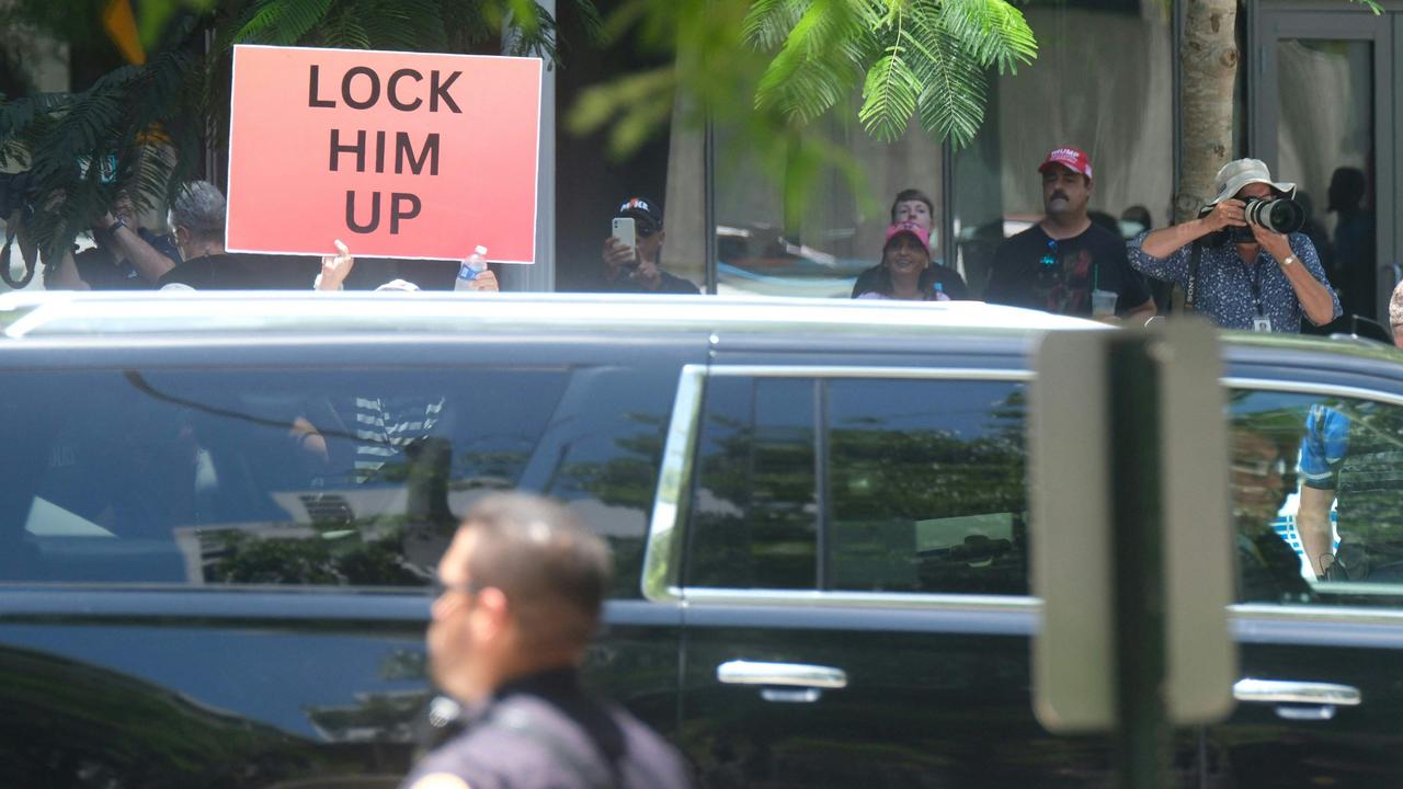 A demonstrator holds a sign as a motorcade of vehicles, with former US President Donald Trump on board, arrives at Federal Courthouse in Miami, Florida. (Photo by RICARDO ARDUENGO / AFP)