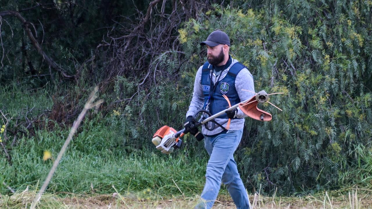 Police paid close attention to a group of trees and shrubs. Picture: Brenton Edwards