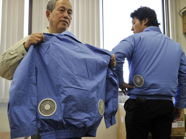 TO GO WITH AFP STORY &Lifestyle-Japan-electricity-disaster, FEATURE& BY MIWA SUZUKI Hiroshi Ichigaya (L) president of Japanese power-saving goods venture &Kuchofuku&, meaning air-conditioned clothing in Japanese, displays a jacket which has cooling fans on its back, at the company's headquarters in Toda city, suburban Tokyo on July 12, 2011. As jackets go it looks far from fashionable, but its Japanese maker cannot meet sky-rocketing demand for &air conditioned& coats with built-in fans. Kuchofuku Co. Ltd -- whose name literally means &air-conditioned clothing& -- has seen orders soar amid power shortages in Japan after the devastating March 11 earthquake and tsunami. AFP PHOTO / Yoshikazu TSUNO