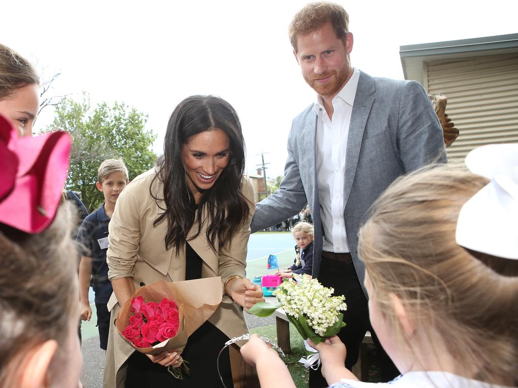 A student presents Meghan Markle with a tiara and flowers at Albert Park Primary School. Picture: David Caird